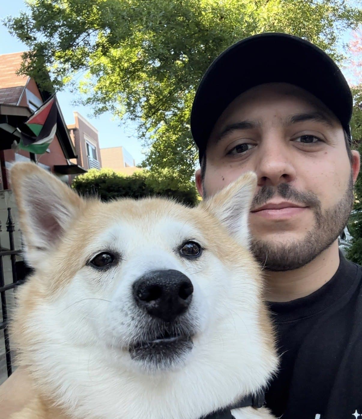 ScadMeta (@ScadMeta) in a black cap taking a selfie with a tan and white dog